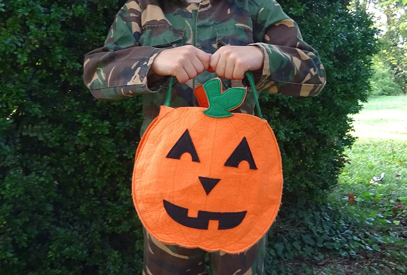 A person in camouflage holding an orange bag.